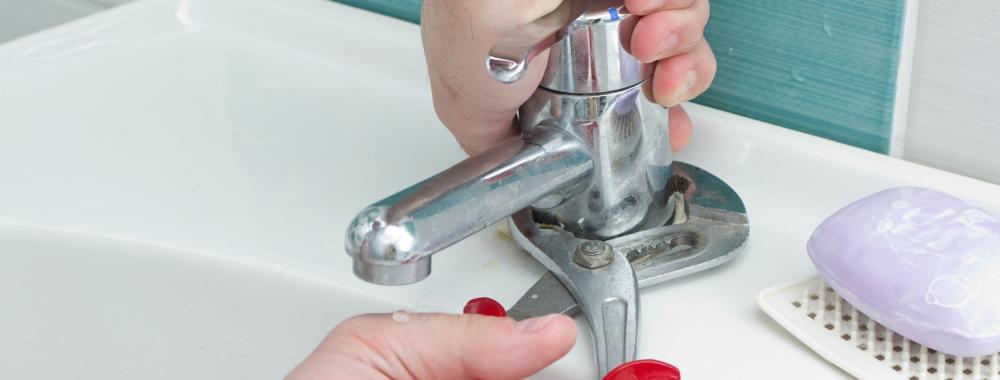 Plumber hands tightning water outlet with pliers.jpg
